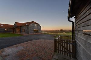 a building with a fence next to a brick driveway at Churchlands Barn in Stone