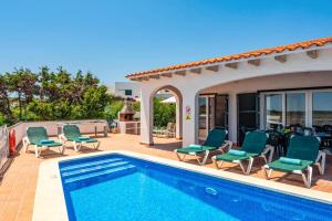 a villa with a swimming pool and patio furniture at Villa Blanc Arenal by Villa Plus in Es Mercadal