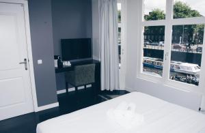 a bedroom with a bed and a desk and a window at Canal House Inn in Amsterdam +13 photos