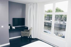 een woonkamer met een televisie en een raam bij Canal House Inn in Amsterdam