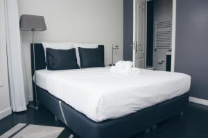 een groot bed met witte lakens en zwarte kussens bij Canal House Inn in Amsterdam