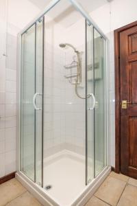 a shower with glass doors in a bathroom at Rose Cottage in Llanbedrog