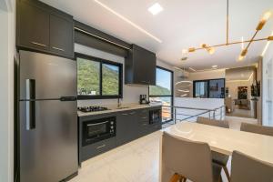 a kitchen with a stainless steel refrigerator and a table at Condomínio Green Ville Residence | Bombinhas | SC in Canto Grande