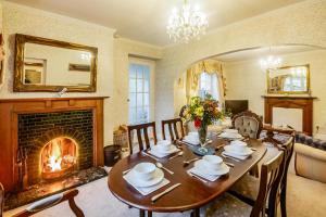 a dining room with a table and a fireplace at North Wing at Penmaen in Pwllheli