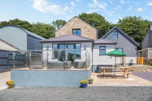 ein Haus mit einem Tisch und einem grünen Sonnenschirm in der Unterkunft Yr Hen Barlwr in Llanddyfnan