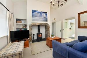 a living room with a blue couch and a fireplace at Pengarth Cottage in Abersoch