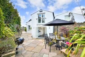a patio with an umbrella and chairs and a house at Pengarth Cottage in Abersoch