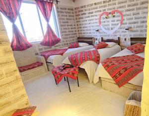 a room with four beds with red curtains and windows at Hotel KAMANA in Chantani