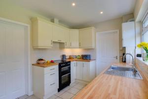 une cuisine avec des armoires blanches et un évier dans l'établissement Ty Gwyn, à Llanbedrog 8 autres photos