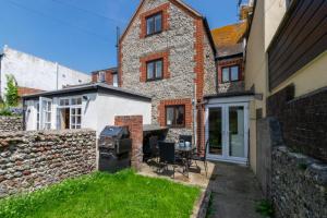 une arrière-cour avec un barbecue et un bâtiment en briques dans l'établissement Pebble Beach Cottage, à Rottingdean