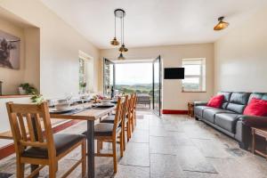 a dining room with a table and chairs and a couch at Greengrove Farmhouse Glasallt in Llangadog