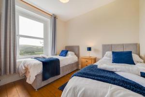 two beds in a bedroom with a window at Greengrove Farmhouse Glasallt in Llangadog