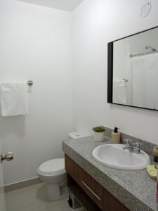 Un baño con lavabo, inodoro y espejo. en Departamento BH South, en Lima