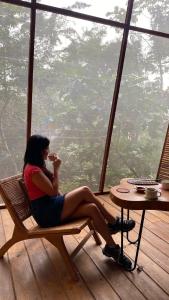 a woman sitting in a chair eating food in front of a window at Tití Bungalows in Tarapoto