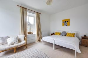 a bedroom with a white bed and a chair at 1 Rose Cottage in Hawes