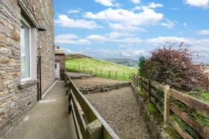 a stone building with a window next to a fence at 1 Rose Cottage in Hawes +4 photos
