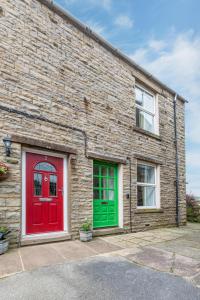 a brick building with a red and green door at 1 Rose Cottage in Hawes