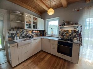 a kitchen with white cabinets and a sink and a window at Hikeslovakia House in Mlynčeky
