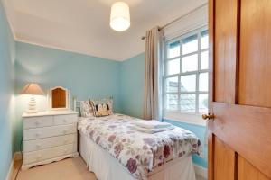 a bedroom with a bed with a dresser and a window at Coastguard Cottage in Blagberry