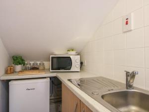 a kitchen with a sink and a microwave at Old Forge Apartment in Wolverley