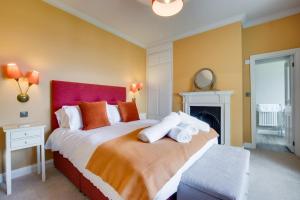a bedroom with a large bed with a red headboard at Orchard Cottage in Newlyn