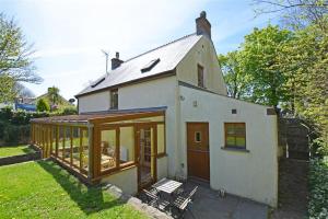 a small white house with sliding glass doors at Chestnut Cottage in Manorbier