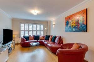 a living room with a leather couch and a flat screen tv at York Mansions Apartment in Broadstairs
