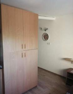 a kitchen with a large wooden cabinet and a clock on the wall at 3 kambariu butas in Klaipėda