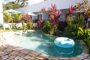 a swimming pool with a lounge chair in a garden at Mar Turquesa Eco Pousada in Maragogi