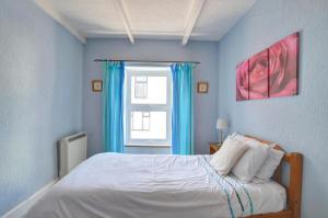 a bedroom with a bed with blue walls and a window at Elvor in New Quay