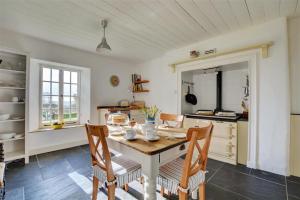 a kitchen with a table and chairs and a kitchen with a counter at The White Cottage in Saint Winnow +18 photos