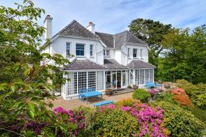 an exterior view of a white house with flowers at Trefaes in Abersoch