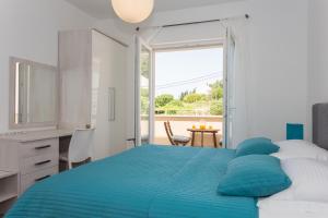 a white bedroom with a blue bed and a table at Apartment & Room Ladisic in Orasac