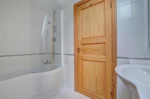 a bathroom with a white tub and a wooden door at 5 Bed in Croyde oc-bonac in Croyde +23 photos