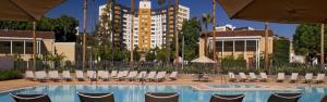 a swimming pool with chairs and umbrellas and a building at Large Elegant Condo with Views near the Grove in Los Angeles