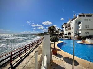 a swimming pool next to the ocean next to a building at Apartamento en Puerta del mar con piscina y wifi - PUERTA DEL MAR CALAHONDA in Mijas Costa