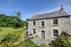 an old stone house with a table and an umbrella at St Teresas Cottage in Saint Mawgan