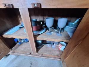 a wooden shelf with cups and dishes in a cabinet at Lindo flat Caxambu Vila Rica Pampulha in Venda Nova