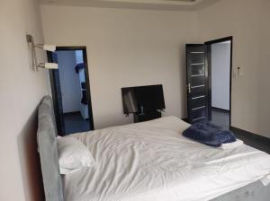 a bedroom with a white bed with a television at casa mara dakar in Bargny