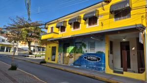 a yellow building on the side of a street at Hotel Brasil in Piquete