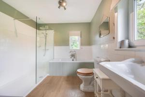 a bathroom with a tub and a toilet and a sink at Higher Treliver Farmhouse in Saint Wenn