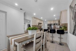 a kitchen with a wooden table and black stools at Modern Cali Comfort- Spacious 3BR Home Near Disneyland & Beaches in Midway City
