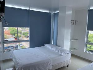 a bedroom with a bed and two windows at Hotel Cristal Oro in Yopal