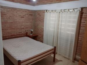 a bedroom with a bed and a brick wall at Depto Los Nidos 4 o 5 personas in Villa Cura Brochero