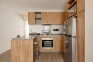 a kitchen with wooden cabinets and a stainless steel refrigerator at Senda Santa Fe Gym WiFi Parking in Cedro