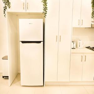 y cocina con nevera y armarios blancos. en The Frederick Guest House, en Sídney