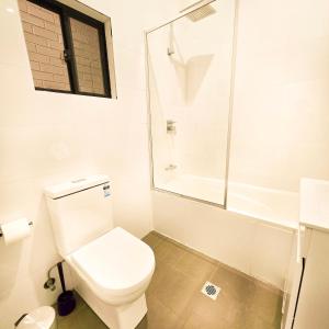 Un baño blanco con inodoro y ducha. en The Frederick Guest House, en Sídney