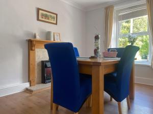 einem Esstisch mit blauen Stühlen und einem Kamin in der Unterkunft Gwenynen Fel Cottage in Burry Port