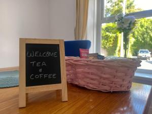 ein Schild mit der Aufschrift „Willkommen Tee und Kaffee“ neben einem Korb in der Unterkunft Gwenynen Fel Cottage in Burry Port + 13 Fotos