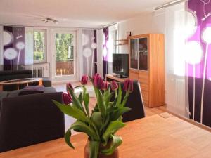 a living room with a table and a vase with purple flowers at Holiday apartment with 3 bedrooms in Enzklösterle